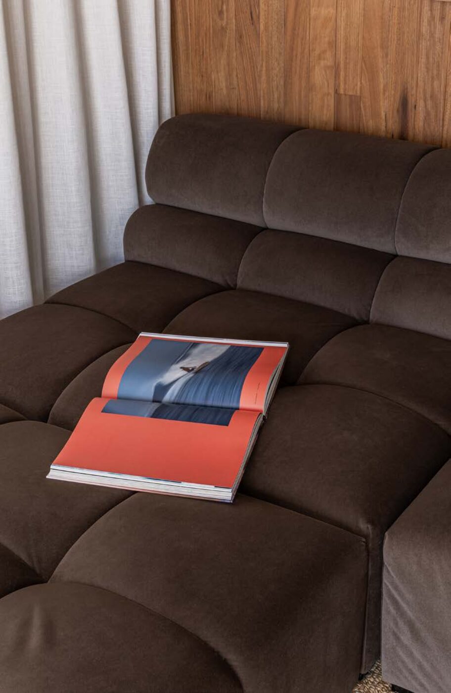 Interior detail — velvet sofa, timber panelling and a surf magazine