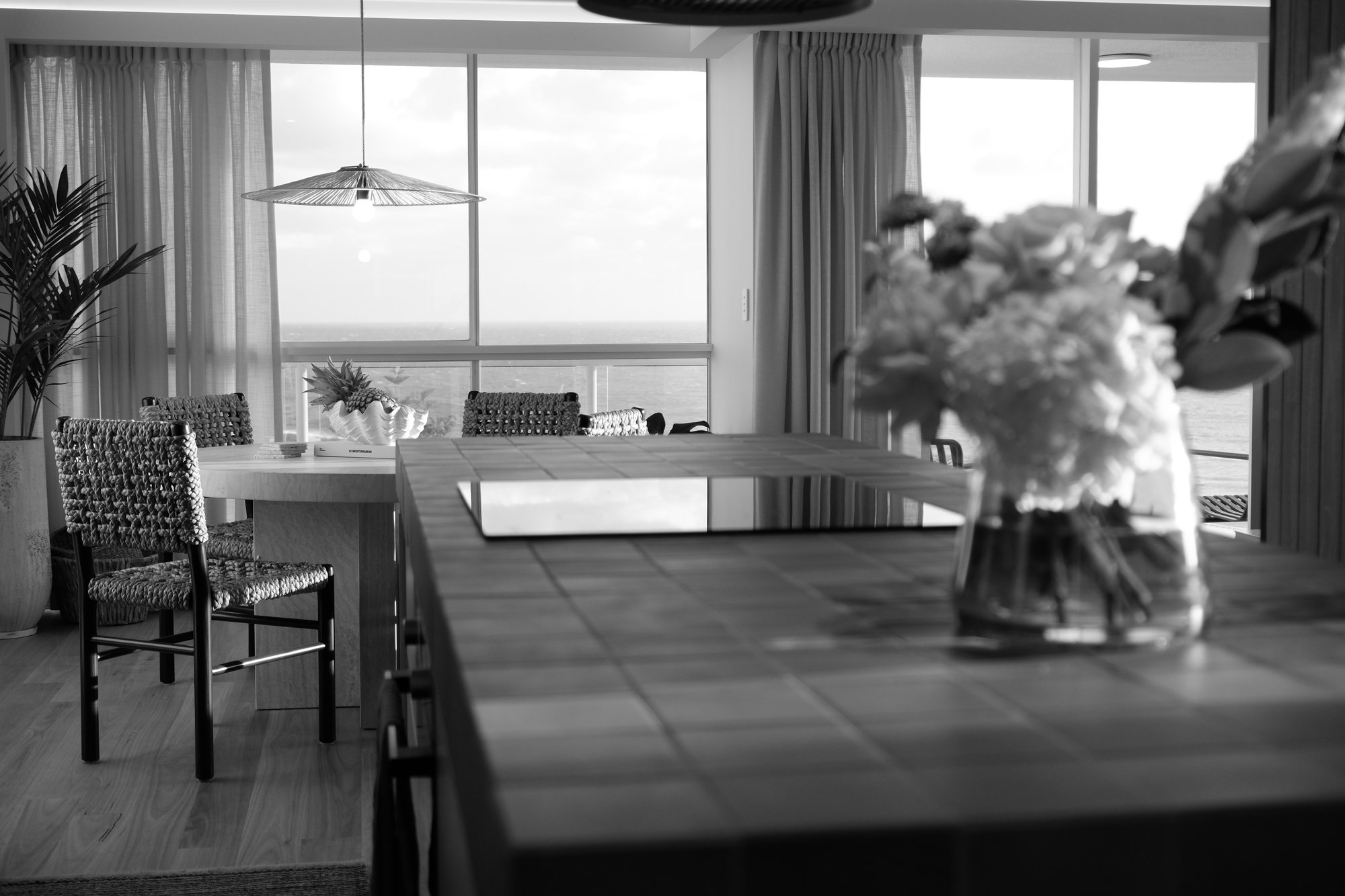 Beachfront dining and living space with ocean views, styled with fresh flowers and timber furniture