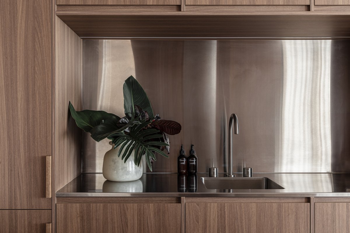 Stainless steel splashback and tapware detail, styled with greenery