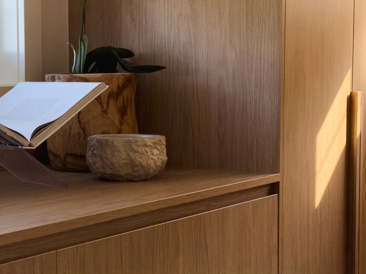 Built-in timber joinery detail with an open book, a carved timber planter and a textured ceramic bowl