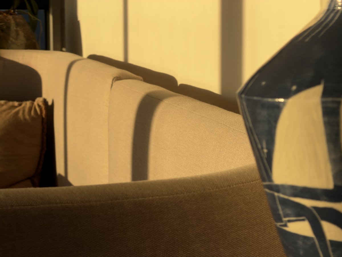 Lounge sofa detail in warm afternoon light, with a cushion and glass side table