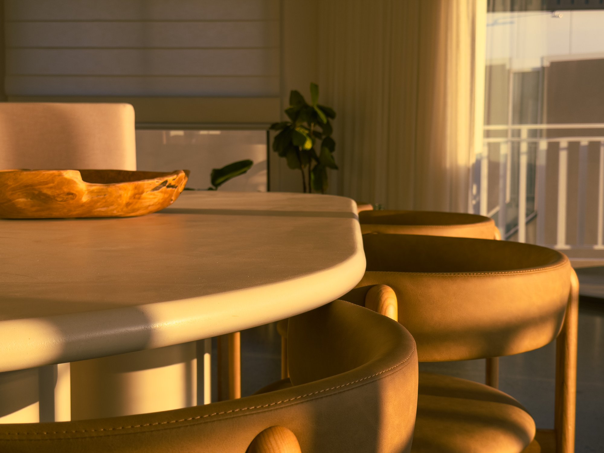 The Dunes — round marble dining table and leather bar stools catching golden-hour light